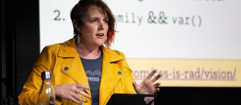 Miriam speaking at Smashing Conf NY in a mustard yellow leather jacket and lightning-bolt pink-blue-white earrings
